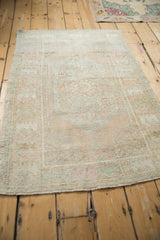Angled view of a vintage Oushak rug highlighting its distressed, low pile and heavy color abrashes.