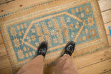 A standing view of a distressed vintage Oushak rug highlighting its scale and dusty blue pattern.