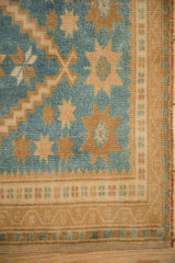 Close view of a distressed Oushak's stepped design, saffron starbursts, and soft bronze border.