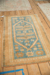 Angled perspective of a distressed Oushak rug with a dusty blue field and saffron gold starbursts.