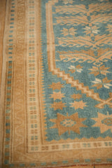 Evenly worn pile on a vintage Turkish rug with a gold border and dusty blue starburst floral design.