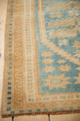 The patterned border and evenly worn low pile of a vintage distressed Oushak rug.