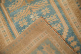 Corner of a distressed Oushak rug folded back to reveal the clean, hand-knotted foundation.