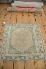 Corner of vintage distressed Oushak rug, pale pink medallion, muted green border starburst vines.