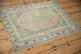 Distressed vintage Oushak rug corner, showing pale pink field and starburst border design.