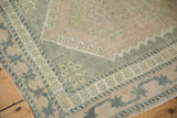 Distressed vintage Oushak rug, showing even wear, with pale pink field and vine starburst border.