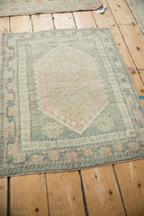 Distressed vintage Oushak rug corner, multi-petaled flower, meandering border, muted pink, olive.