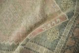 Textural detail of vintage distressed Oushak rug with soft pile in pale pink, olive, and silver.
