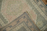 Distressed Oushak rug's soft pale pink and olive pile, revealing a patterned, muted beige reverse.