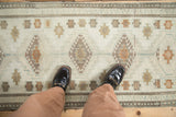 Ivory, gold, and brown geometric gul medallions on a distressed vintage Oushak rug runner underfoot.