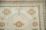 Hand-knotted Oushak runner with geometric border, distressed ivory field, and pale gold motifs.