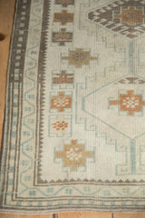 Distressed Oushak runner's textured pile, highlighting ivory, saffron, and pale blue patterns.