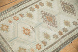 Distressed Oushak runner's ivory field showing simplistic medallions and heavy pale coffee abrashes.