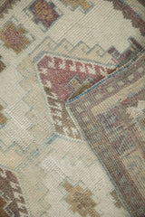 Distressed vintage Oushak rug texture showing worn geometric motifs in ivory, raspberry, brown, and blue selvage with reverse.