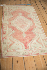 Distressed Oushak rug edge showing faded pale red and ivory geometric patterns.