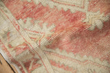 Distressed Oushak rug's worn pile, showing brick red and ivory geometric pattern detail.