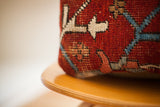 Hand-knotted texture of a vintage Persian rug pillow with deep red, blue, and cream patterns.