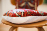 Side view of a hand-knotted vintage Persian rug pillow with textured red, blue pattern and white suede.