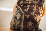 Close-up of antique Turkish rug pillow featuring hand-knotted texture and tribal animal motifs.