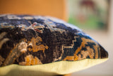 Side of antique Turkish rug pillow, highlighting dark hand-knotted fragment and muted lime green corduroy.