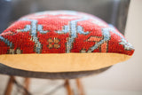 Textured red and blue vintage Persian rug pillow backed with mustard yellow velvet.