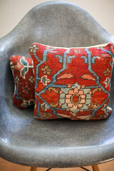 Intricate central pattern on the red vintage Persian rug pillow, featuring light blue, peach, and tan.