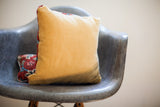 Mustard yellow velvet pillow, red Persian rug fragment side, with smaller accent pillow.