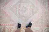A top-down personal view of the distressed Oushak rug, showing its scale and worn texture.