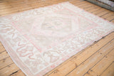 Angled view of a vintage Oushak carpet, emphasizing its low, even wear and faded geometric design.