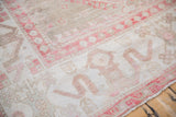 Expressive cloudband border detail in pink and ivory on a distressed vintage Oushak carpet.
