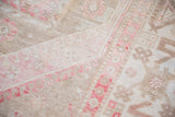 Worn knot heads reveal the soft texture of a vintage Oushak in blush, beige, and ivory.