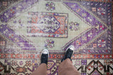Distressed vintage Oushak rug showcasing faded aubergine, seafoam green, rust geometric motifs.