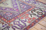 Distressed vintage Oushak rug corner, violet field and geometric cloudband border.