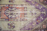 Distressed vintage Oushak rug detail: violet, seafoam green, dusty rust hues, serrated florals, foundation showing.
