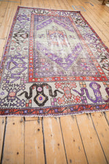 Vintage distressed Oushak rug end showing visible wear, fringe, and geometric violet-rust patterns.