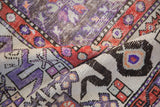 Distressed Oushak rug with violet, rusty red, ivory geometric motifs, showing worn pile texture.
