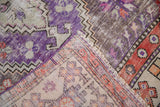 Distressed vintage Oushak rug corner with wear to knot heads, violet zigzag pattern, and machine bound edge.