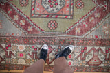 Worn texture and geometric cloudband border on a distressed Oushak carpet in sage and copper.