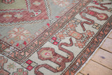 Geometric cloudband border in copper and sage green on a distressed vintage Oushak rug.