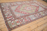 Expressive geometric cloudband border in copper and sage on a distressed vintage Oushak rug.