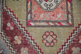 Low pile detail on a distressed Oushak with copper and sage green geometric floral patterns.