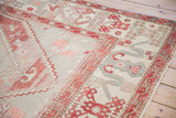 Vintage Oushak rug field with pinwheel florals, cloudband border, and distressed copper tones.