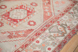 Distressed Oushak rug corner, geometric cloudband border, serrated copper florals, ivory, mostly even wear.