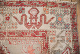 Distressed Oushak rug corner showing geometric cloudband border in copper, ivory, and slate blue.