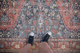 Interconnected floral blossoms on distressed Sparta carpet in navy, terra cotta, and ivory.