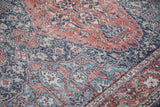Distressed texture of the vintage Sparta rug, with worn floral motifs in terra cotta and navy.
