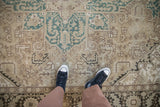Distressed Turkish Heriz carpet with geometric arabesques in dusty teal, ivory, and brown tones.