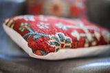 Close-up of vintage Persian rug pillow, red and blue hand-knotted pattern, white suede backing.