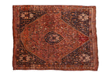 Vintage Persian Qashqai carpet, asymmetric medallion with scattered animal motifs in chestnut, navy, rust.