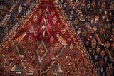 Detailed view of Qashqai carpet's madder root, navy, tangerine tribal motifs.